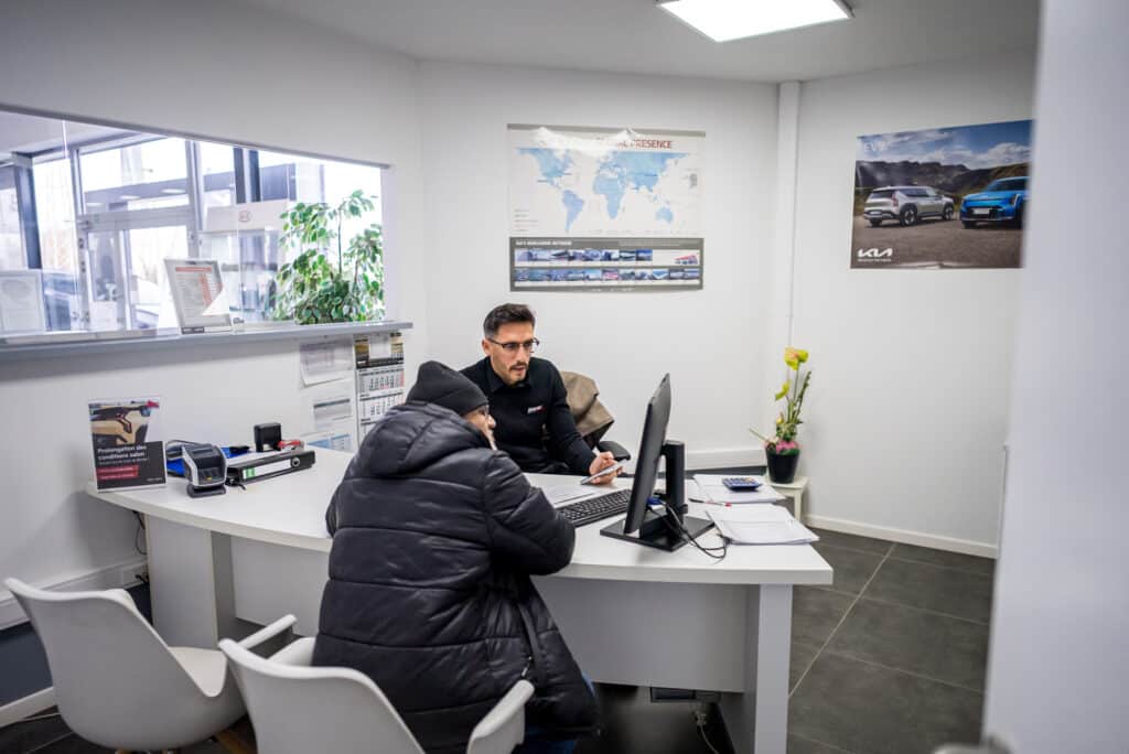 Vendeur du garage Incar Motor à Ans accompagnant un client dans la configuration de son véhicule dans un bureau dédié.