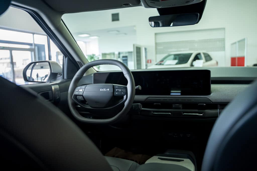 Vue intérieure du volant d’une Kia dans le showroom du garage Incar Motor à Ans, mettant en avant le design et les fonctionnalités du poste de conduite.