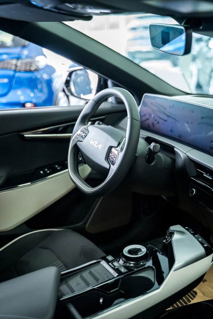 Vue intérieure du cockpit d’une Kia dans le showroom du garage Incar Motor à Ans, mettant en avant le design et les fonctionnalités du poste de conduite.
