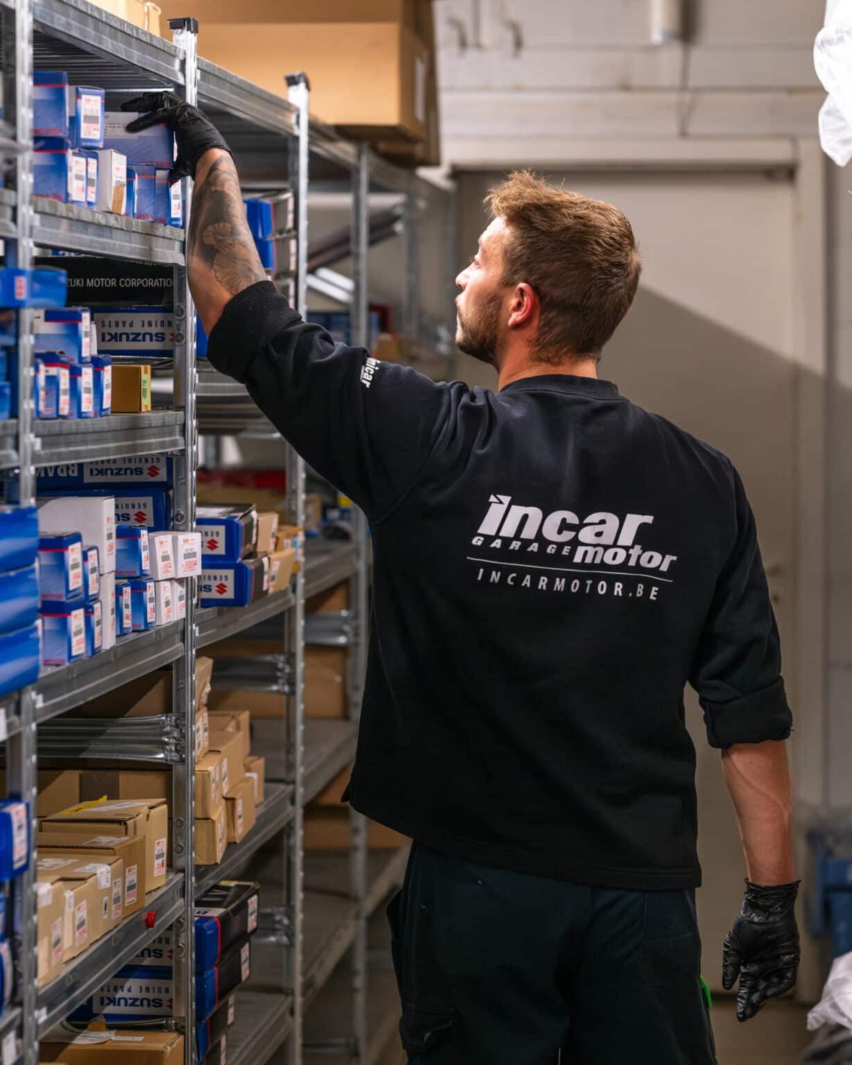 Employé du garage Incar Motor à Arlon recherchant une pièce détachée dans l’espace dédié.